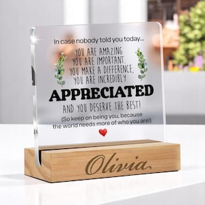 Könnte beinhalten: Eine klare Acryl-Plakette mit einem Holzsockel, auf dem der Name "Olivia" eingraviert ist. Die Plakette zeigt eine Botschaft mit dem Text "Falls dir das heute noch niemand gesagt hat... Du bist fantastisch. Du bist wichtig. Du machst einen Unterschied. Du bist unglaublich geschätzt. Und du verdienst das Beste! (Bleib einfach du selbst, denn die Welt braucht mehr Menschen wie dich!)"