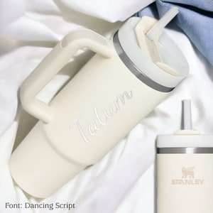 Pu&ograve; includere: Bicchiere termico color crema con manico, cannuccia e coperchio. Il nome "Tatum" &egrave; inciso sul lato in corsivo. &Egrave; visibile anche un bicchiere pi&ugrave; piccolo abbinato, con il logo "Stanley".