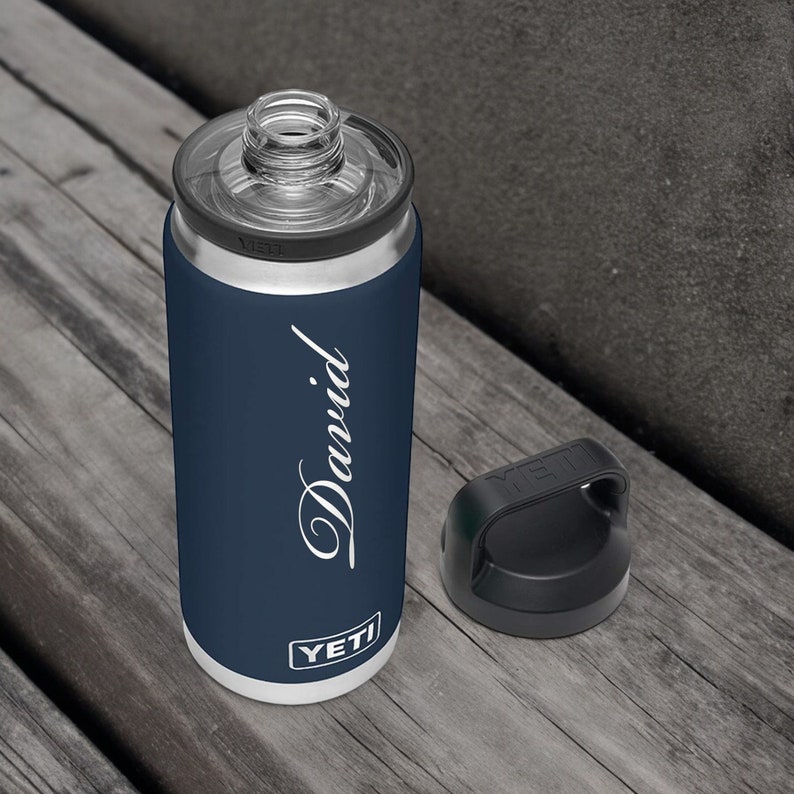 Puede incluir: Una botella de agua aislada azul marino con el nombre "David" en escritura blanca. La botella tiene una tapa transparente y una tapa negra. La marca "YETI" est&aacute; impresa en la parte inferior.