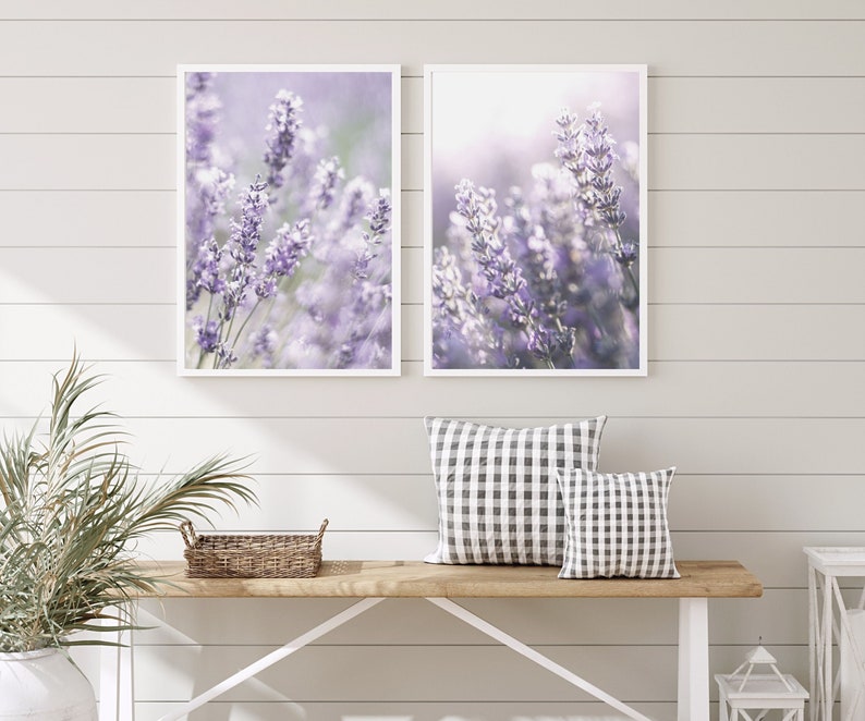 Puede incluir: Dos impresiones enmarcadas de flores de lavanda en un tono morado suave. Las impresiones est&aacute;n colgadas en una pared blanca de tablones de madera sobre un banco de madera con dos almohadas a cuadros.