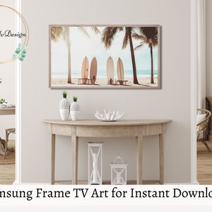 May include: A digital art print of surfboards on a beach with palm trees. The print is in a light brown frame and is hanging on a wall above a wooden console table. The print is perfect for a beach-themed home decor.