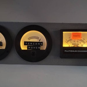 May include: Three black gauges with illuminated faces. The left gauge reads "PRIMARY", the middle gauge reads "PERCENT POWER", and the right gauge reads "PLUTONIUM CHAMBER" with a red label that says "EMPTY".