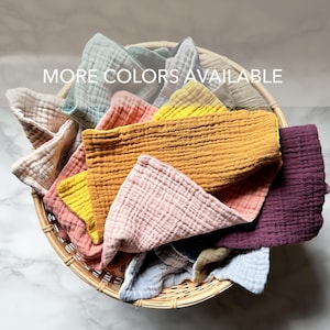 May include: A woven basket filled with a variety of colorful, textured cloths. The cloths are in shades of pink, yellow, orange, teal, and purple. The text "MORE COLORS AVAILABLE" is visible.