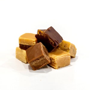 May include: A close-up of a pile of fudge squares. The fudge is a mix of brown, tan, and white.