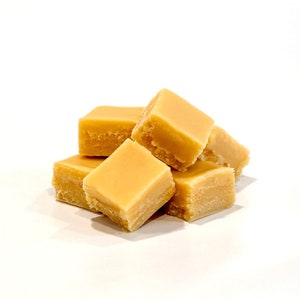 May include: A close-up of a pile of five soft, pale yellow fudge squares.