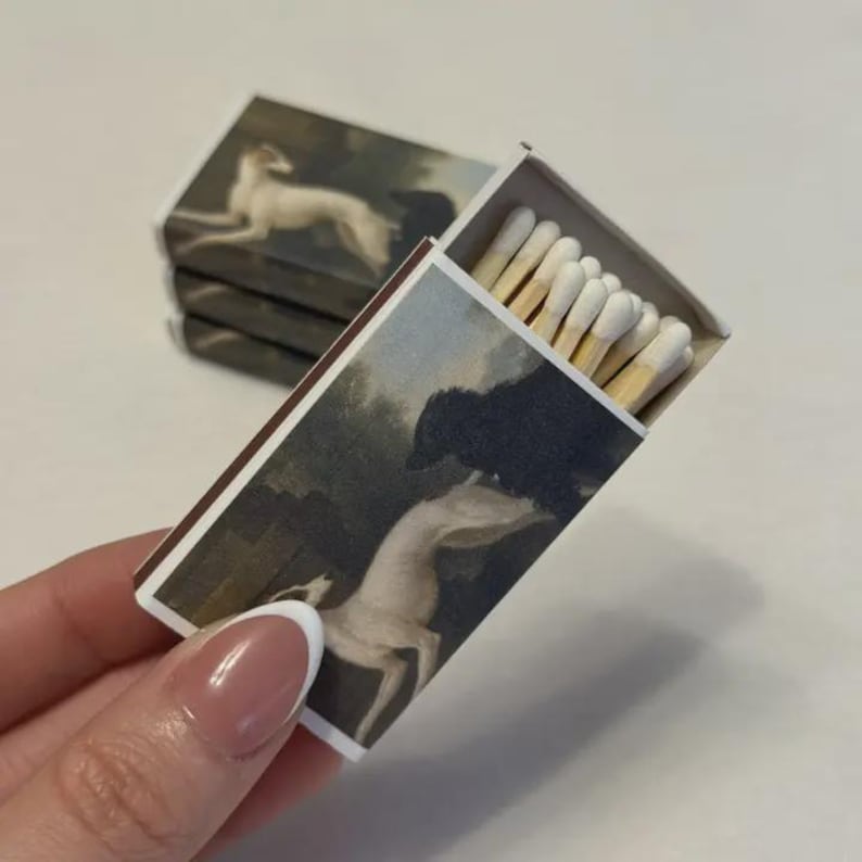 May include: A white ceramic mug with a black handle and the text "But First, Coffee" in a bold, black font. The mug sits on a white surface, showcasing its clean design.