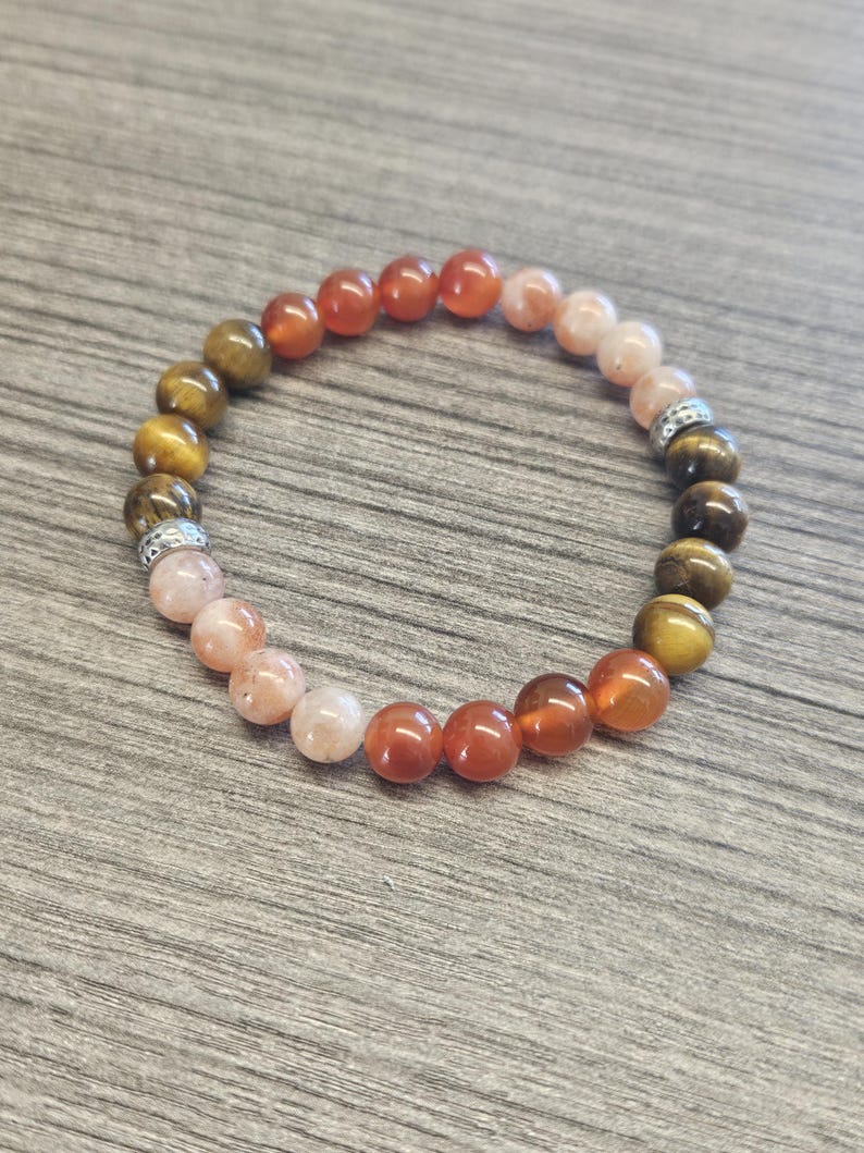 May include: A multi-colored beaded bracelet with brown, orange, and pink beads. The bracelet has silver accents.
