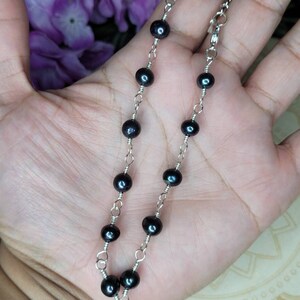 May include: A delicate silver chain necklace with black pearl beads. The necklace is approximately 18 inches long and features a lobster clasp closure.