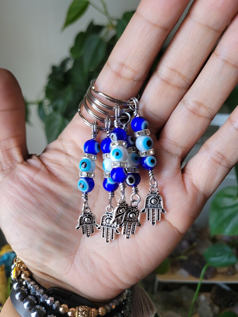 May include: Five silver keychains with blue and white evil eye beads and silver hamsa hand charms.