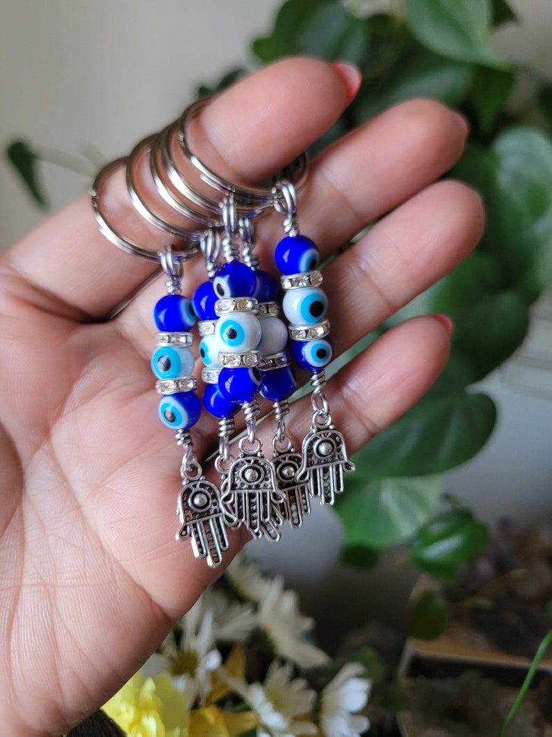 May include: Five silver keychains with blue and white evil eye beads and silver hamsa hand charms.
