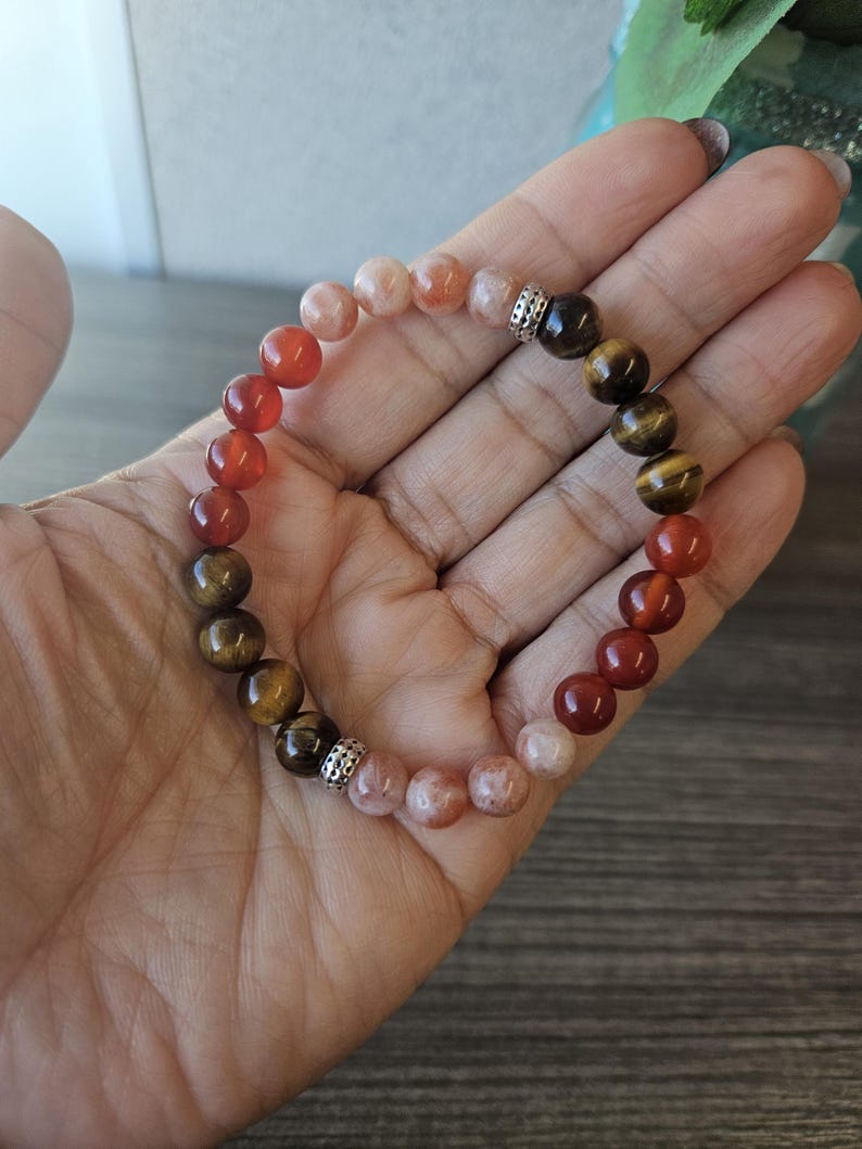 May include: A bracelet made with carnelian, tiger's eye, and sunstone beads. The beads are separated by silver spacers.