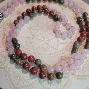 May include: A double-strand mala necklace with pink rose quartz and green and brown jasper beads.
