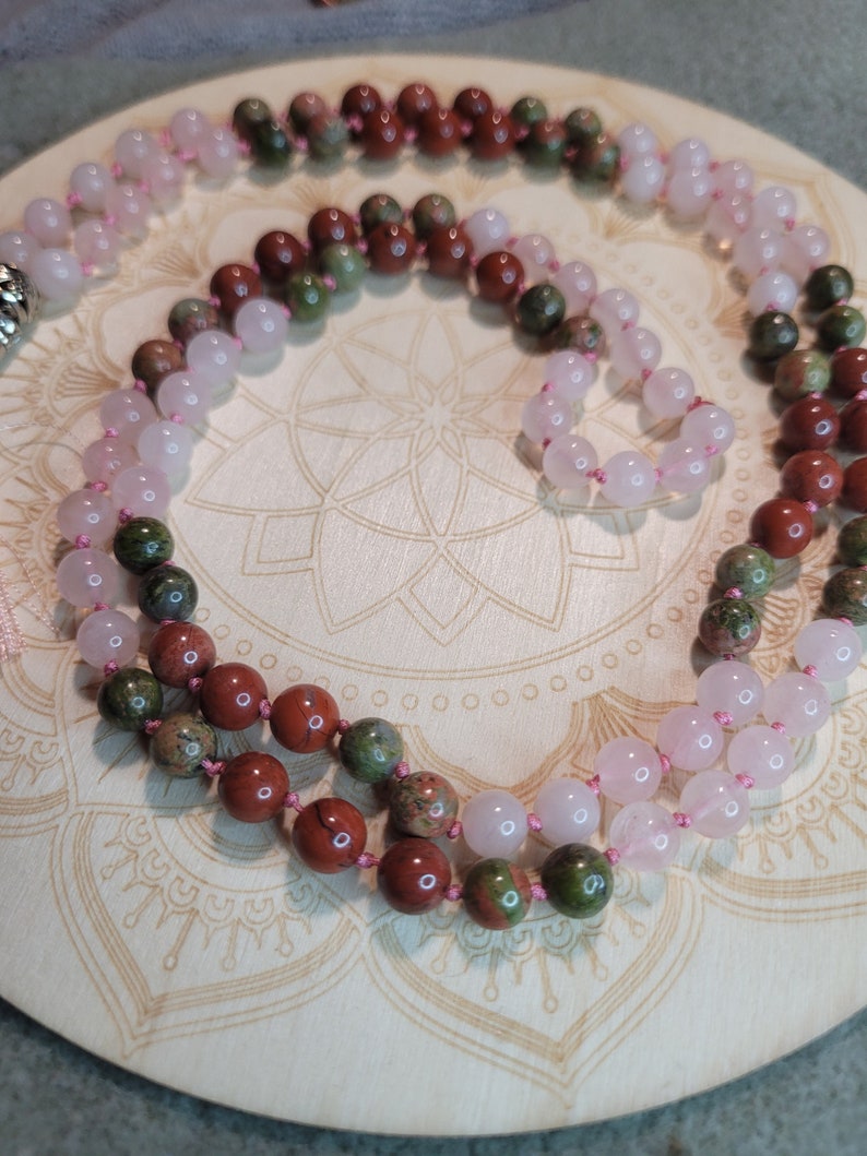 May include: A double-strand mala necklace with pink rose quartz and green and brown jasper beads.