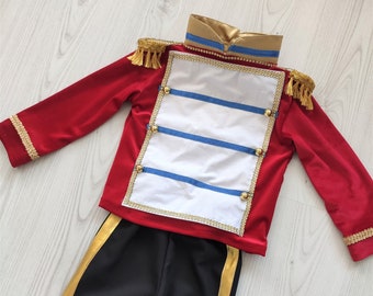 May include: A red and black costume for a child, featuring a red jacket with gold trim and a white panel with blue stripes, and black pants with gold stripes.