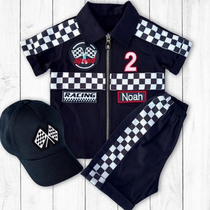 May include: A black and white checkered racing outfit for a child. The outfit includes a short-sleeved jacket with a zip, a pair of trousers, and a black baseball cap. The jacket has patches that say "Speed", "Racing", and "Noah". The trousers have a black and white checkered stripe down the side. The cap has a checkered flag design.