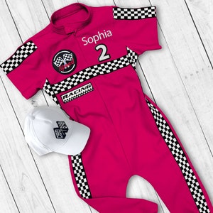 May include: Pink racing jumpsuit with black and white checkered accents. The jumpsuit has a white patch with the word "Speed" and a checkered flag design. The jumpsuit also has a white patch with the word "Racing". The jumpsuit has the name "Sophia" and the number "2" on the front. A white baseball cap with a black and white checkered flag design is included.