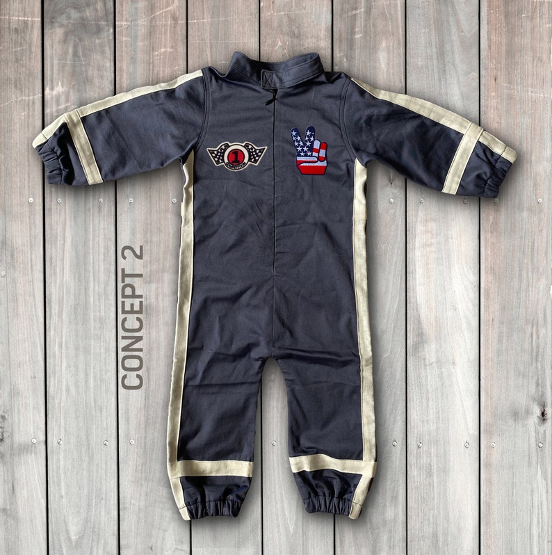 May include: A dark gray jumpsuit with white stripes down the sides. The jumpsuit has a zipper in the front and a patch on the chest with a number 1 and wings. There is also a patch on the right side with a peace sign and an American flag.