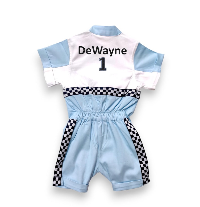 May include: A light blue jumpsuit with a white panel on the back. The panel has the name "DeWayne" and the number "1" in black. The jumpsuit has black and white checkered trim on the sleeves and legs.