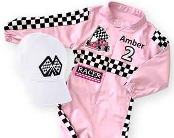 Könnte beinhalten: Ein rosa Rennanzug und eine weiße Baseballkappe. Der Anzug hat schwarz-weiß karierte Akzente, den Namen "Amber" und die Nummer "2". Ein Aufnäher auf dem Anzug lautet "RACER". Die Kappe hat ein kariertes Flaggenlogo.