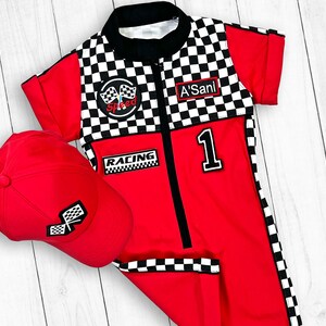 May include: Red and black checkered racing suit with a zipper in the front, a black "Speed" patch with a checkered flag, a black "Racing" patch, and a black "1" patch. The suit is paired with a red baseball cap with a checkered flag.