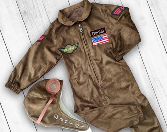 May include: Brown suede pilot jumpsuit with a zipper closure, a patch that says "Air Force", a name tag that says "Daniel", and a small American flag patch. The jumpsuit comes with a matching brown suede pilot hat with a leather strap and the name "Daniel" embroidered on it.