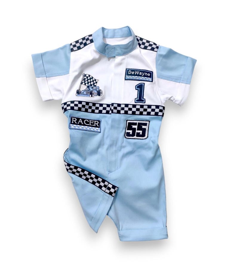 May include: A light blue racing jumpsuit with black and white checkered trim. The jumpsuit has patches that say "DeWayne", "Racer", and "55". There is also a patch with a cartoon race car.