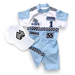 May include: A blue and white racing suit with a checkered pattern and the name "DeWayne" and the number "1" on the front. The suit also has the number "55" on the front and the word "RACER" on the chest. A white baseball cap with a checkered flag design is included.