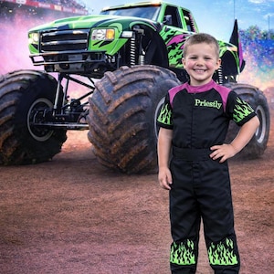 May include: A young person in a black jumpsuit with green flame accents stands in front of a large green and black monster truck. The jumpsuit has the name "Priestly" on the chest. The background shows a stadium and a blue sky.