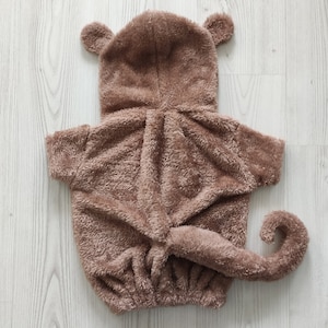 Puede incluir: Un disfraz de mono de peluche marr&oacute;n con capucha y cola. El disfraz est&aacute; hecho de tela suave y peluda y tiene un dise&ntilde;o lindo y juguet&oacute;n.