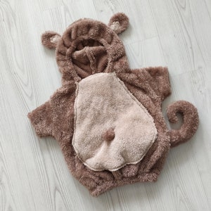 Puede incluir: Un disfraz de mono de peluche marr&oacute;n con capucha y cola. El disfraz est&aacute; hecho de tela suave y peluda y tiene un dise&ntilde;o lindo y juguet&oacute;n.