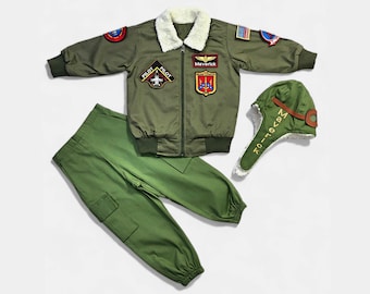 May include: An olive green bomber jacket with a white faux-fur collar, featuring various embroidered patches including 'Maverick' and 'Pilot', paired with matching olive green cargo pants and an aviator-style cap with 'Maverick' embroidered on the side.