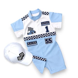 May include: A light blue and white short-sleeve romper with a checkered pattern, featuring the name DeWayne, the number 1, the number 55, and the word RACER. A white baseball cap with a black and white checkered flag emblem is included.