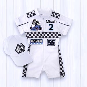 May include: White racing-themed romper and cap set. The romper features black and white checkered accents, the name "Micah" and the number "2". A blue race car and checkered flag are also displayed. The cap has a checkered flag design.