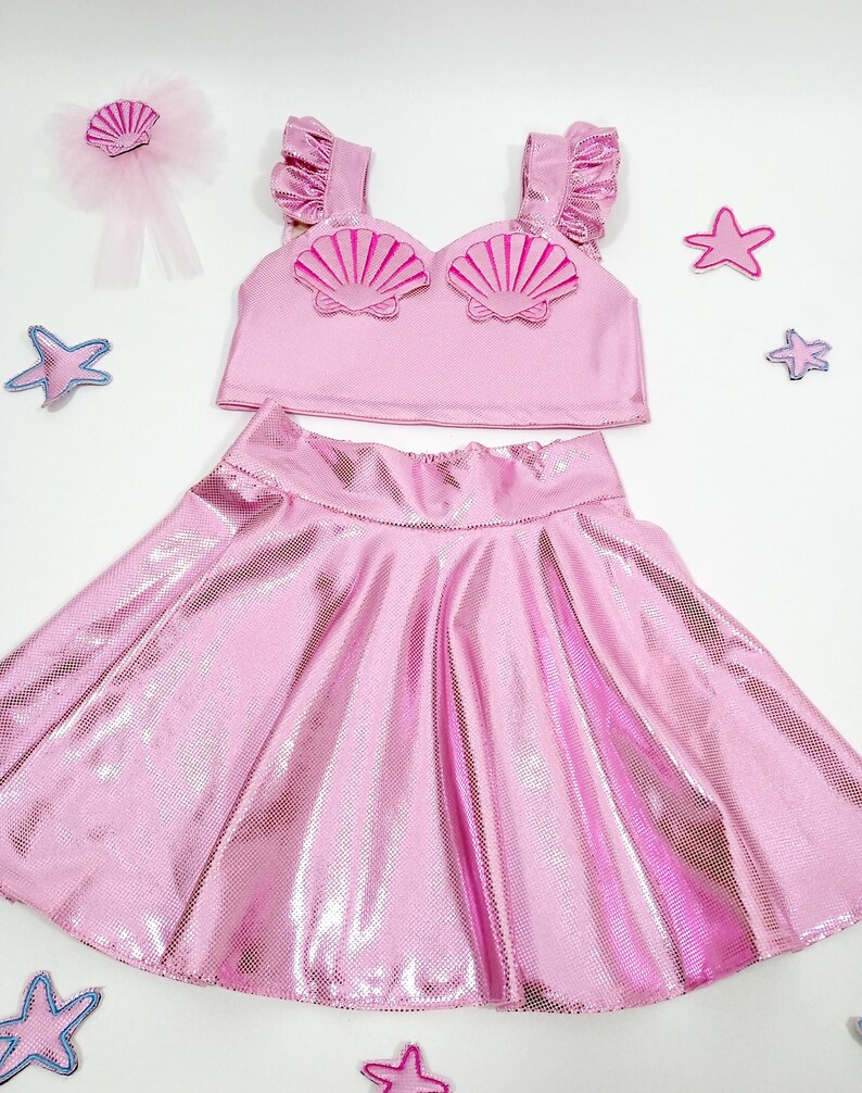 May include: A pink mermaid costume for girls, featuring a sparkly skirt and a crop top with pink seashell embellishments.