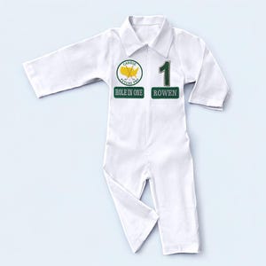 A professional flat lay of the long-sleeved white golf caddy costume. The garment is spread out to show the elastic waistband, the structured collar, and the symmetrical placement of the green patches. This clean layout allows shoppers to visualize the overall silhouette and design of the uniform at a single glance.
