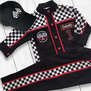 May include: Black and white checkered racing jumpsuit with red trim and a name tag that says "DAVID" and the number "1". The jumpsuit also has a black and white checkered patch with the word "Speed" on it. A black baseball cap with a checkered flag design is included.