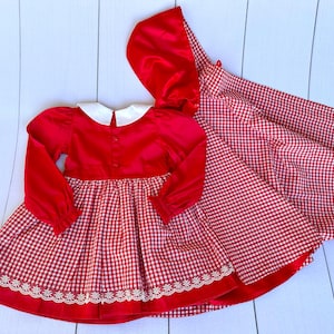K&ouml;nnte beinhalten: Rot-wei&szlig;es Gingham-Kleid mit rotem Samt-Oberteil und wei&szlig;em Kragen. Das Kleid hat einen wei&szlig;en Spitzenbesatz und wird mit einer passenden roten Samt-Kapuzenjacke geliefert.