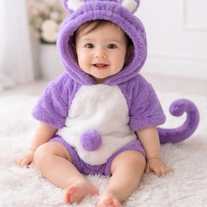 May include: A purple and white plush animal-themed romper featuring a hood with ears, short sleeves, a white belly panel, a small pom-pom detail on the front, and a long, curled tail attached to the back of the garment for a textured look.