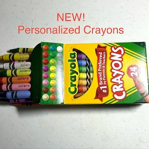 May include: A box of 24 Crayola crayons with the text NEW! Personalized Crayons. The box is yellow and green with a cutout showing the crayons inside. Each individual crayon is labeled with the name Juliana in black text on the wrapper.