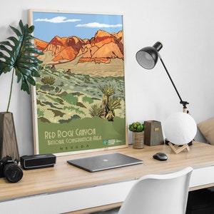 K&ouml;nnte beinhalten: Ein Vintage-Poster mit einer malerischen Illustration des Red Rock Canyon National Conservation Area in Nevada. Das Poster zeigt eine Bergkette mit roten Felsformationen und eine W&uuml;stenlandschaft mit gr&uuml;ner Vegetation. Der Text "Red Rock Canyon National Conservation Area Nevada" ist am unteren Rand des Posters gedruckt.