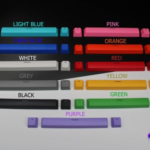 Pu&ograve; includere: Una collezione di tasti colorati per tastiera in vari colori, tra cui azzurro, blu scuro, rosa, arancione, rosso, giallo, verde e viola. Ogni set include un tasto lungo e due tasti pi&ugrave; piccoli. I testi "LIGHT BLUE", "DARK BLUE", "PINK", "ORANGE", "RED", "YELLOW", "GREEN" e "PURPLE" sono visualizzati.