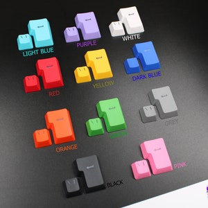 Puede incluir: Un conjunto de teclas de teclado coloridas en varios tonos, incluyendo azul claro, morado, blanco, rojo, amarillo, azul oscuro, naranja, verde, gris, negro y rosa. Cada juego de teclas incluye dos piezas. El texto "YOURCUSTOMKEYS" es visible.