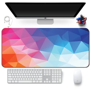 Può includere: Un ampio tappetino per mouse rettangolare con un design geometrico nei toni dell'arancione, rosa, viola e blu. Una tastiera, un mouse e un monitor per computer sono posizionati sopra. Sono visibili anche un portapenne e delle cuffie.