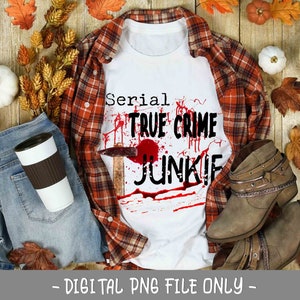 Puede incluir: Una camiseta blanca con un gr&aacute;fico rojo y negro que dice "Serial True Crime Junkie". La camiseta est&aacute; sobre una camisa de franela a cuadros, jeans azules y decoraciones de oto&ntilde;o.