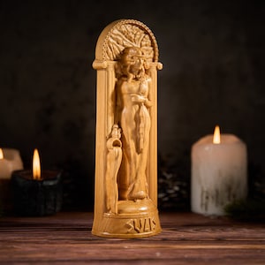 May include: A wooden statue of a woman with a tree behind her, standing in a carved archway. The statue is light brown and has the word "Sulis" carved at the bottom.