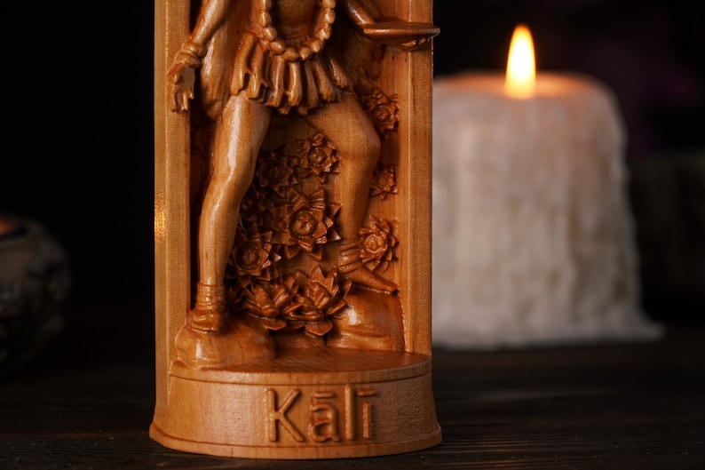 Pu&ograve; includere: Scultura in legno dettagliata della dea ind&ugrave; Kali. La scultura presenta intricati dettagli della sua forma e del suo abbigliamento. Lo sfondo sfocato mette in risalto i toni caldi del legno e il tema spirituale.