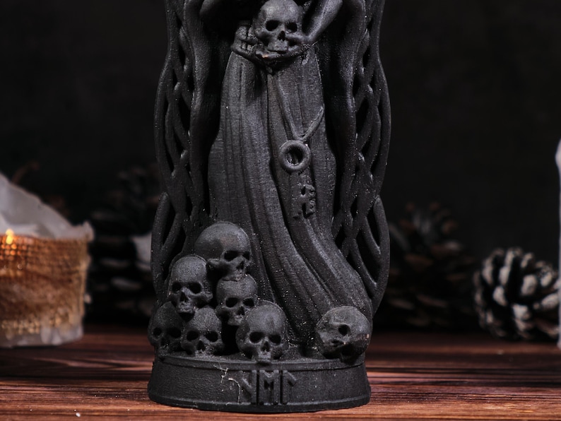 Puede incluir: Estatua negra de la Parca con base adornada con calaveras y una capa con capucha. La estatua presenta m&uacute;ltiples calaveras en la base y un colgante en forma de llave. Tema g&oacute;tico.