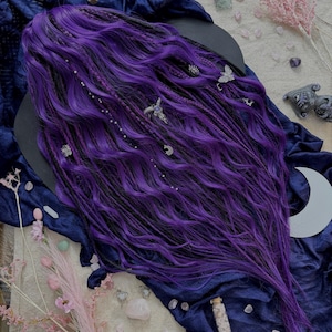 a purple wig with intricate braids and various crystals and flowers scattered around it, creating a mystical and enchanting atmosphere.