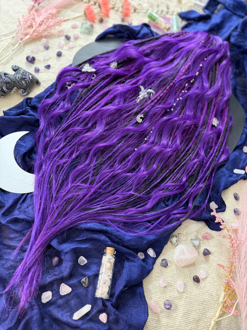 a long, vibrant purple wig with intricate braids and various crystals and gemstones scattered around it, creating a mystical and enchanting atmosphere.