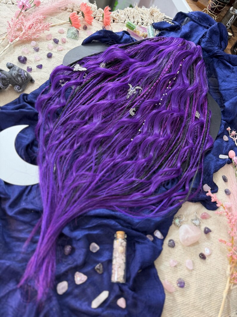 a long, vibrant purple wig with intricate braids and various crystals and gemstones scattered around it, creating a mystical and enchanting atmosphere.